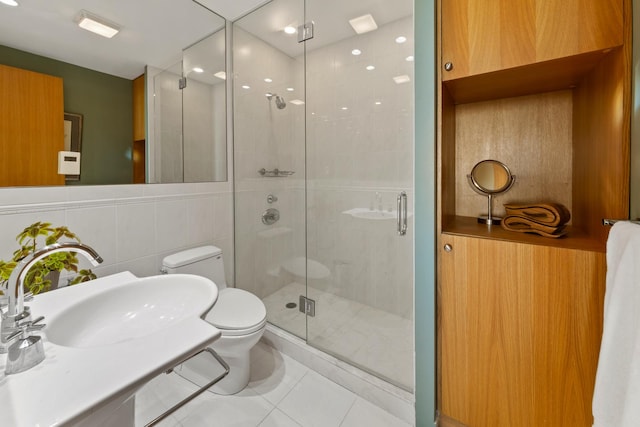 bathroom featuring tile patterned floors, toilet, an enclosed shower, sink, and tile walls