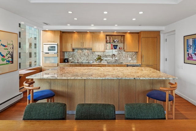 kitchen with backsplash, a breakfast bar area, light stone countertops, and dark hardwood / wood-style floors