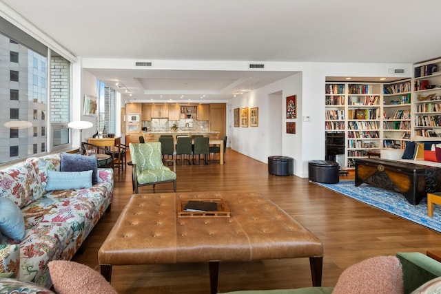 living room featuring wood-type flooring and a tray ceiling