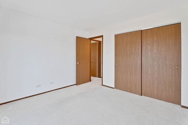 unfurnished bedroom with light colored carpet and a closet