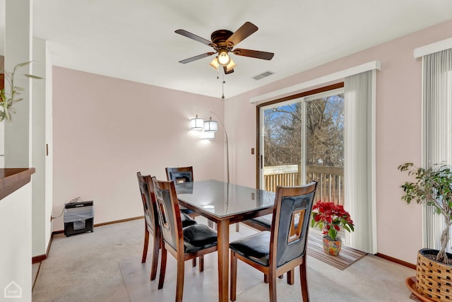 dining space with ceiling fan and light colored carpet