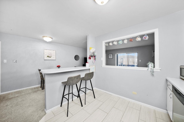 kitchen with appliances with stainless steel finishes, light colored carpet, a kitchen bar, and kitchen peninsula