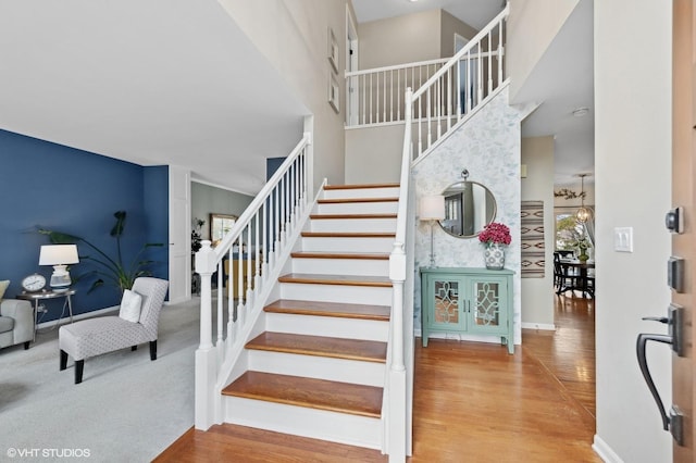 stairway with a high ceiling, baseboards, and wood finished floors