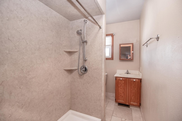 bathroom with vanity, toilet, and tiled shower