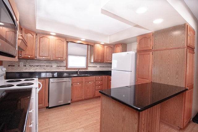 kitchen featuring a kitchen island, tasteful backsplash, sink, a raised ceiling, and white appliances