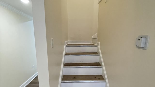 stairway with hardwood / wood-style flooring and ornamental molding