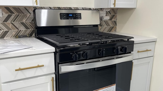 kitchen featuring white cabinetry, decorative backsplash, and gas range oven