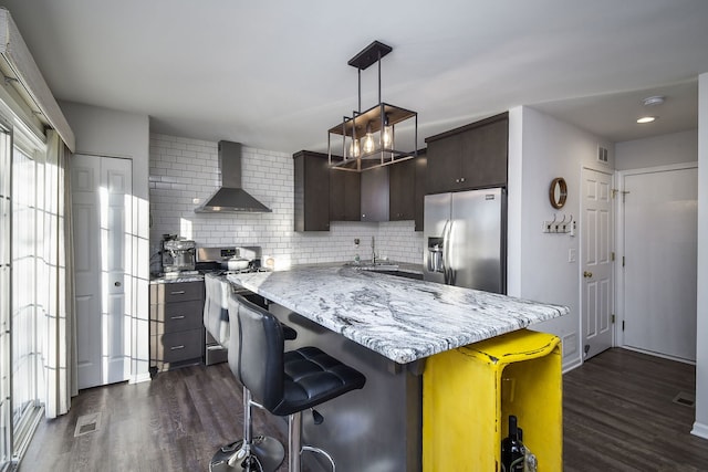 kitchen featuring appliances with stainless steel finishes, dark hardwood / wood-style floors, a kitchen island, and wall chimney range hood