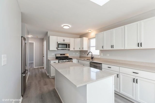 kitchen featuring a kitchen island, sink, white cabinets, hardwood / wood-style flooring, and stainless steel appliances