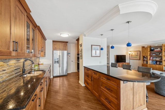 kitchen featuring appliances with stainless steel finishes, a breakfast bar, hardwood / wood-style floors, sink, and hanging light fixtures