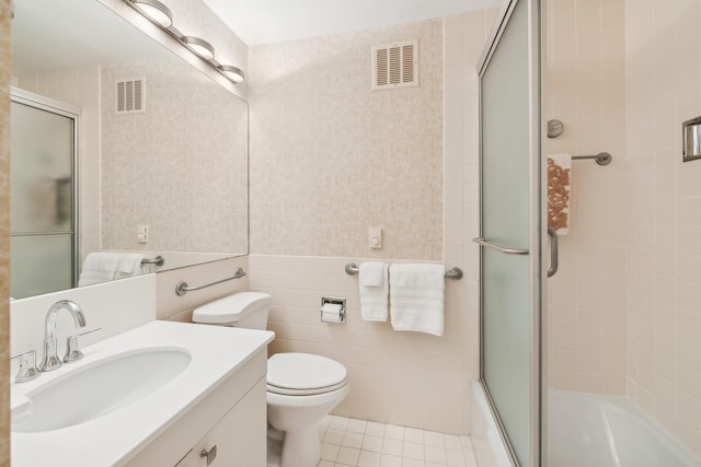 full bathroom featuring tile walls, bath / shower combo with glass door, vanity, tile patterned floors, and toilet