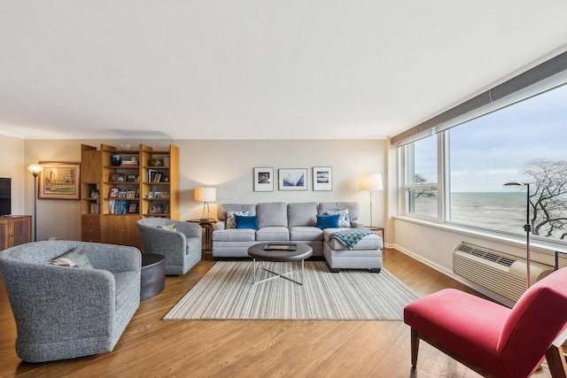 living room featuring hardwood / wood-style flooring, a water view, and a wall mounted AC