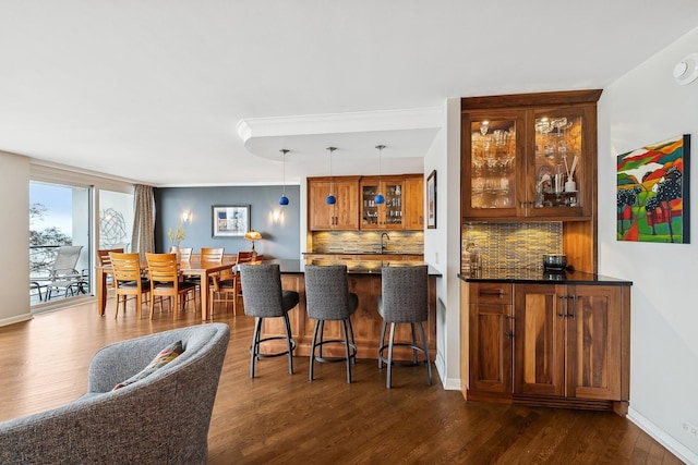 bar featuring hanging light fixtures, dark wood-type flooring, and backsplash