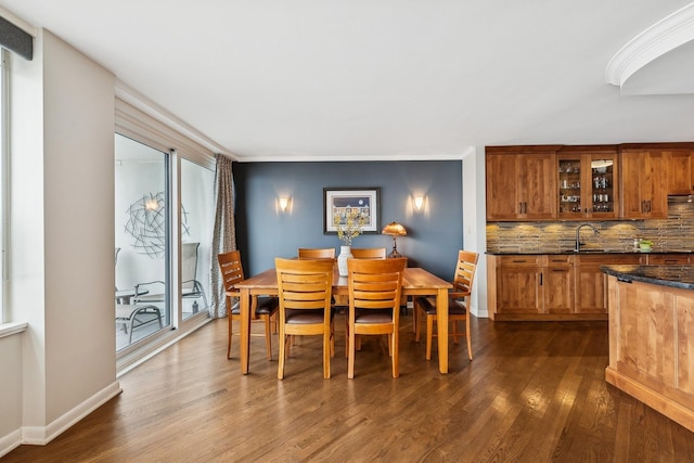 dining room featuring sink, ornamental molding, and dark hardwood / wood-style floors