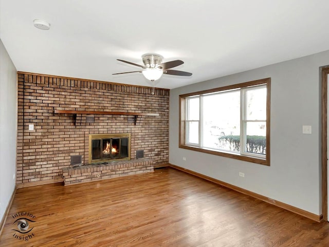 unfurnished living room with wood-type flooring, ceiling fan, and a fireplace