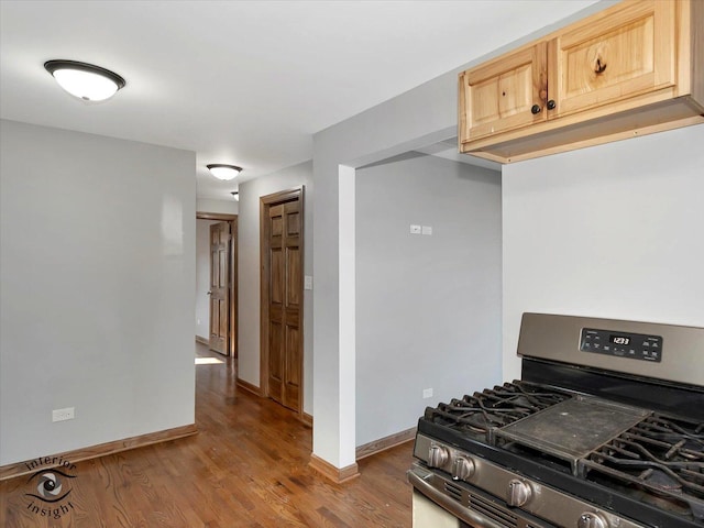 kitchen with light brown cabinetry, stainless steel gas range oven, and wood-type flooring