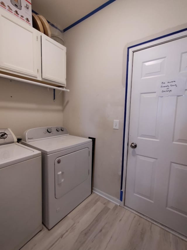 laundry room featuring separate washer and dryer, light hardwood / wood-style flooring, and cabinets