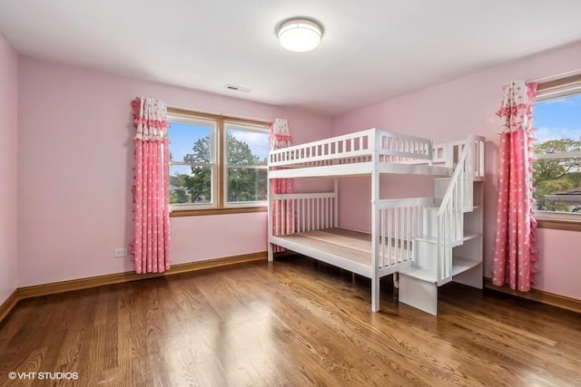 unfurnished bedroom featuring visible vents, baseboards, and wood finished floors