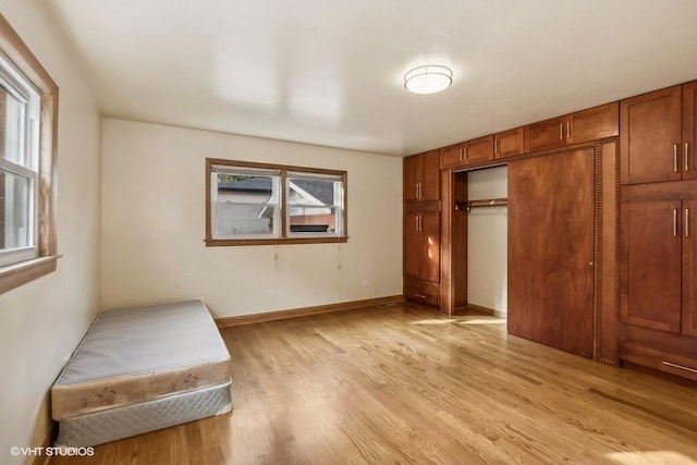 unfurnished bedroom with light wood-type flooring, a closet, and baseboards