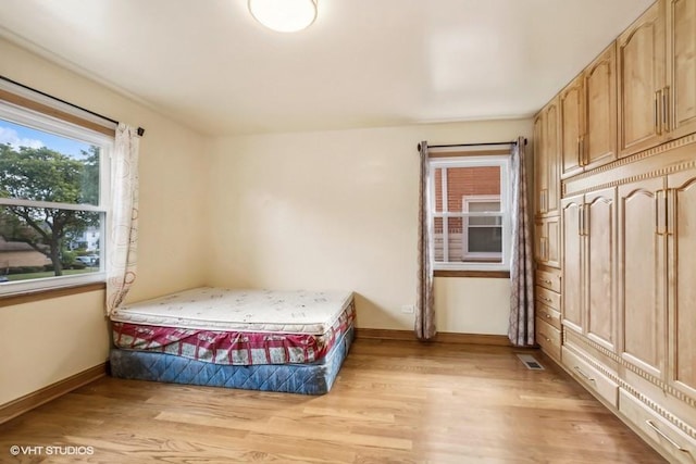 bedroom featuring visible vents, light wood-style flooring, and baseboards