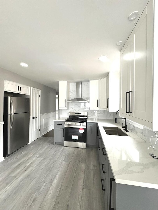 kitchen featuring wall chimney exhaust hood, sink, gray cabinetry, white cabinetry, and stainless steel appliances