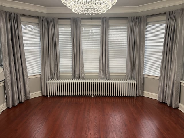 spare room with ornamental molding, radiator heating unit, dark hardwood / wood-style flooring, and a notable chandelier