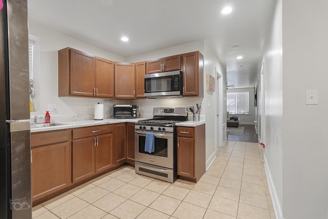 kitchen featuring stainless steel appliances, light tile patterned flooring, and sink