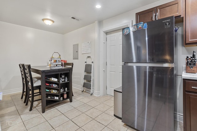 kitchen with stainless steel refrigerator, electric panel, dark brown cabinets, and light tile patterned floors