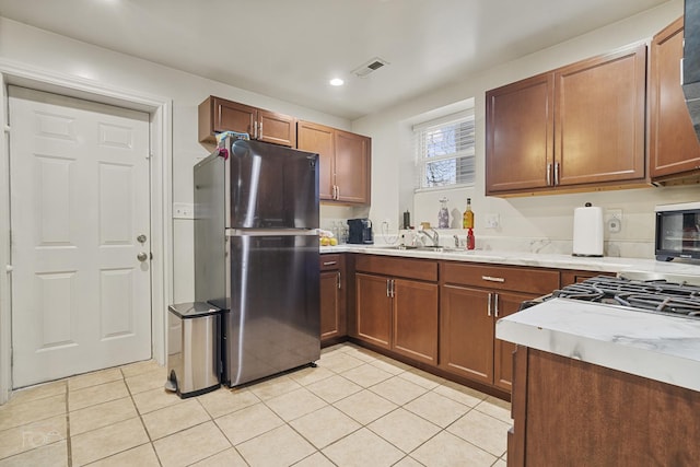 kitchen featuring sink, stainless steel refrigerator, and light tile patterned flooring