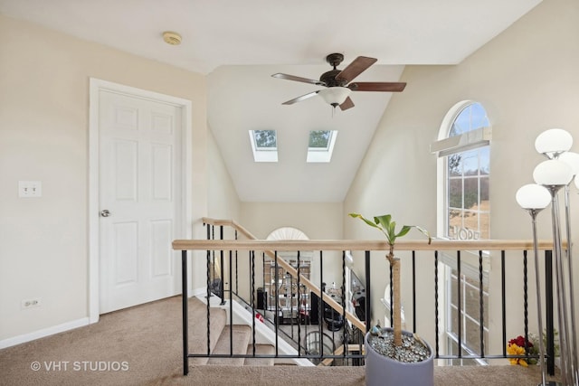 staircase featuring ceiling fan, carpet flooring, and lofted ceiling with skylight