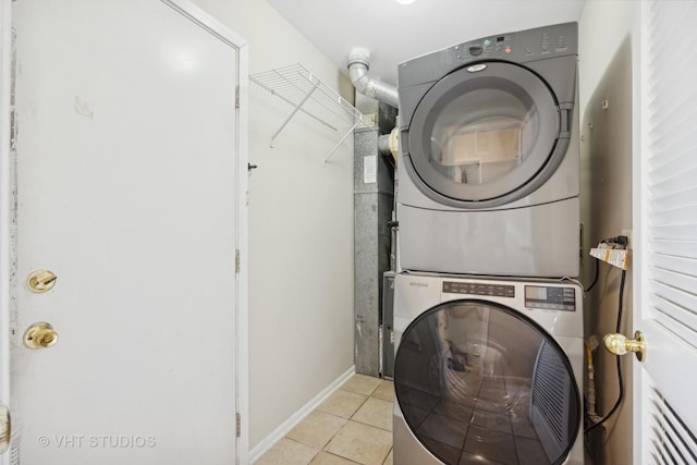 laundry area with light tile patterned floors and stacked washer and clothes dryer