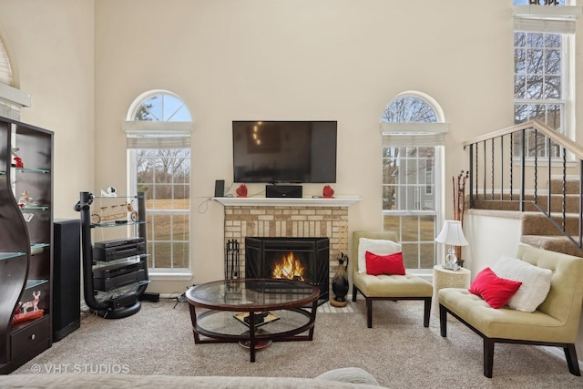 living room featuring carpet floors, a fireplace, and a high ceiling