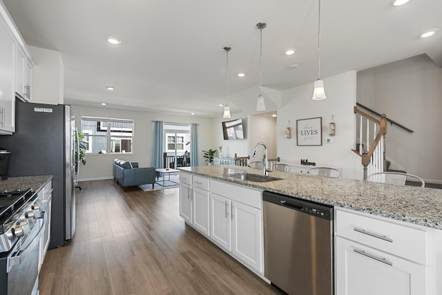 kitchen featuring decorative light fixtures, white cabinetry, sink, stainless steel appliances, and light stone countertops