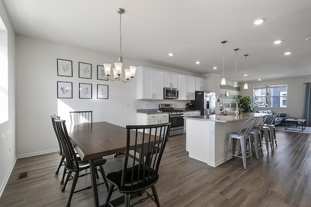 dining area featuring dark wood-type flooring, sink, and a notable chandelier