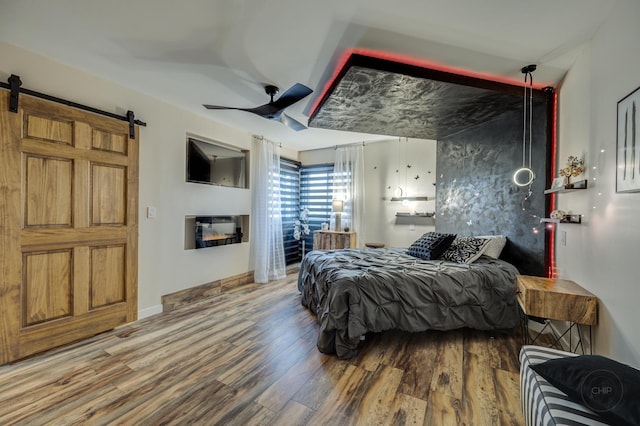 bedroom featuring hardwood / wood-style floors, a barn door, and ceiling fan