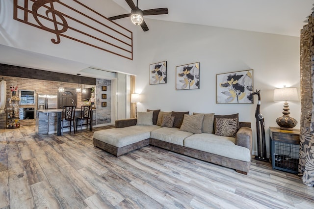 living room with hardwood / wood-style flooring, ceiling fan, and high vaulted ceiling