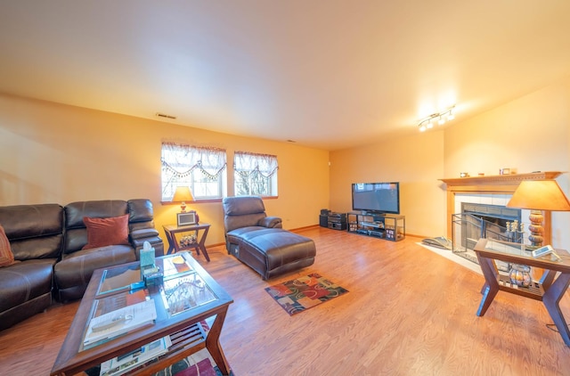 living room with hardwood / wood-style flooring, a tile fireplace, and rail lighting