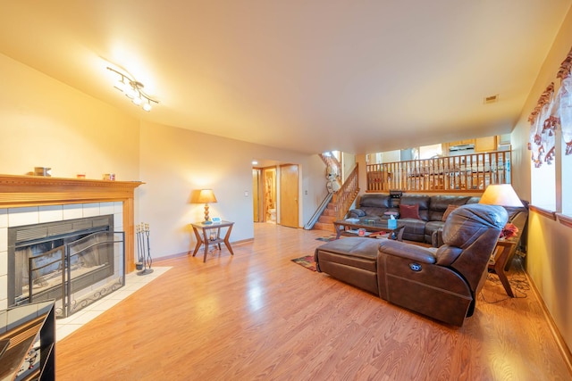 living room with wood-type flooring and a tile fireplace