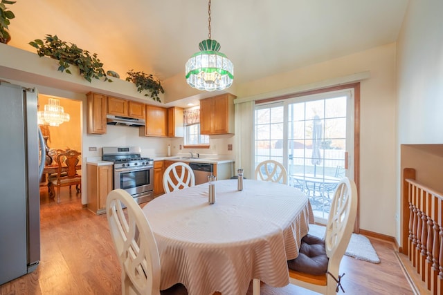 dining space with sink, light hardwood / wood-style flooring, and a notable chandelier