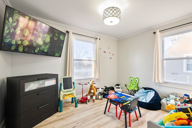 recreation room featuring crown molding, a wealth of natural light, and light wood-type flooring