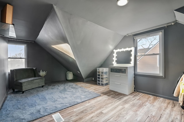 additional living space with a healthy amount of sunlight, vaulted ceiling, and light wood-type flooring