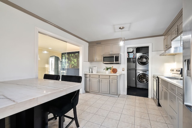 kitchen featuring stacked washer / dryer, ornamental molding, appliances with stainless steel finishes, and pendant lighting