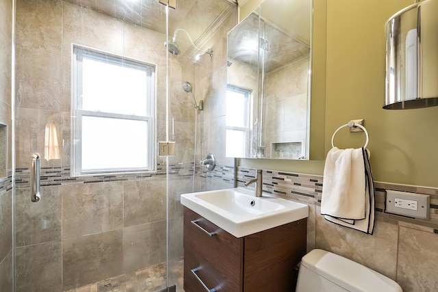 bathroom featuring tile walls, backsplash, vanity, a shower with shower door, and toilet