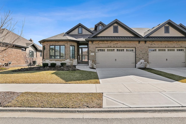 craftsman-style house with brick siding, a front lawn, concrete driveway, an attached garage, and a standing seam roof