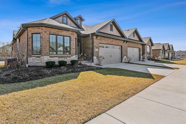 view of front facade featuring a front lawn, driveway, stone siding, a garage, and brick siding