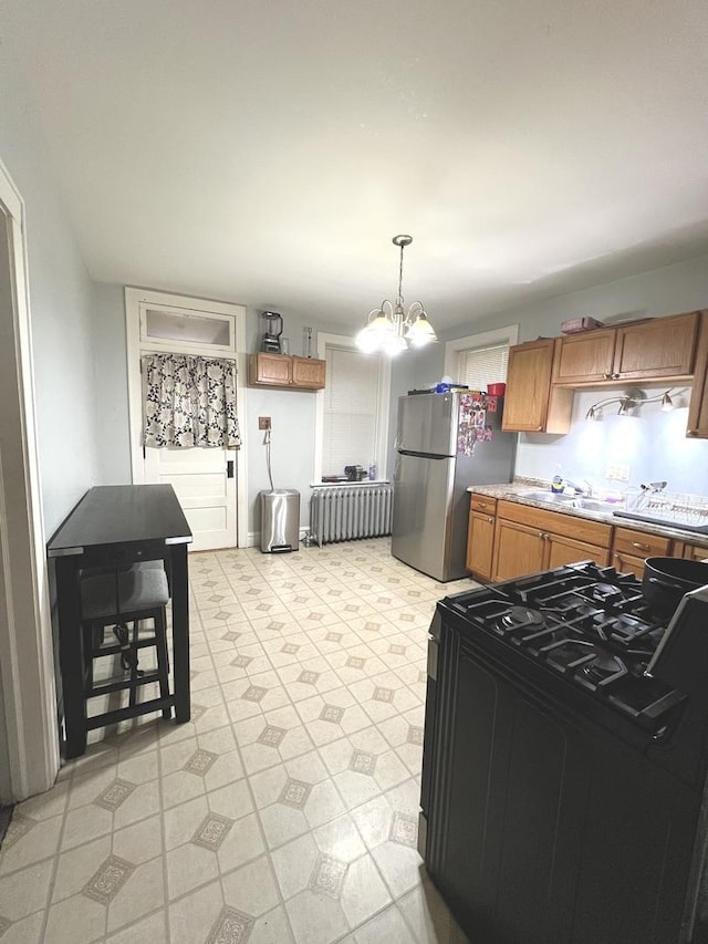 kitchen with stainless steel refrigerator, an inviting chandelier, black gas range, hanging light fixtures, and radiator heating unit