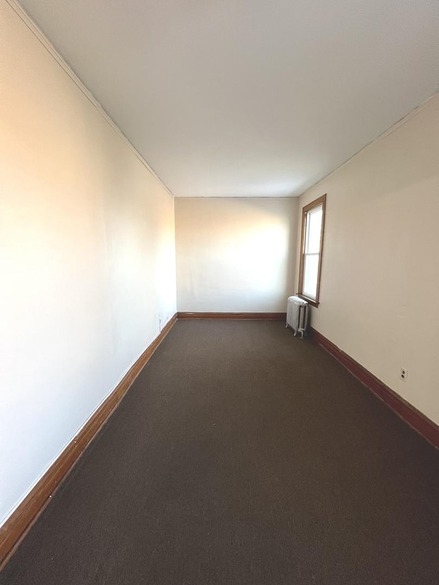 carpeted empty room featuring radiator heating unit