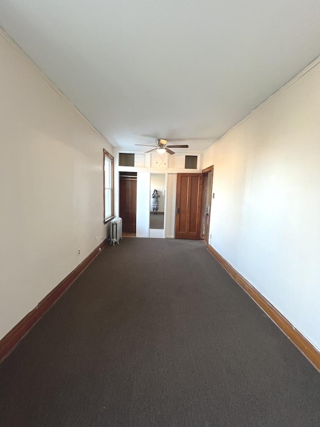 unfurnished living room with carpet, radiator heating unit, and ceiling fan