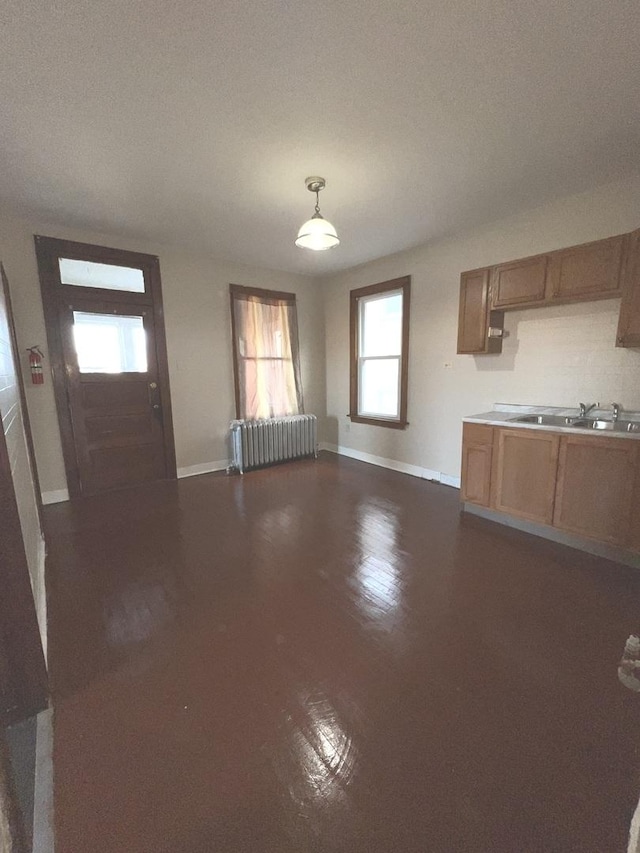 unfurnished living room featuring radiator and sink