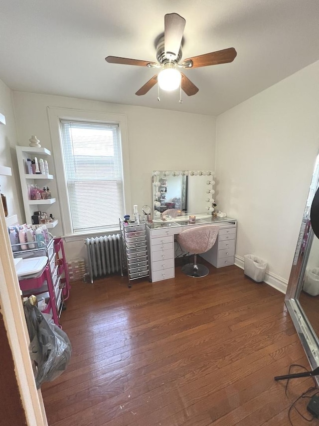 home office with dark hardwood / wood-style flooring, radiator heating unit, and ceiling fan